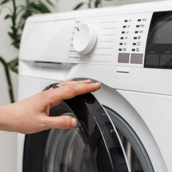 Une personne en train de toucher le bouton d'une machine à laver.